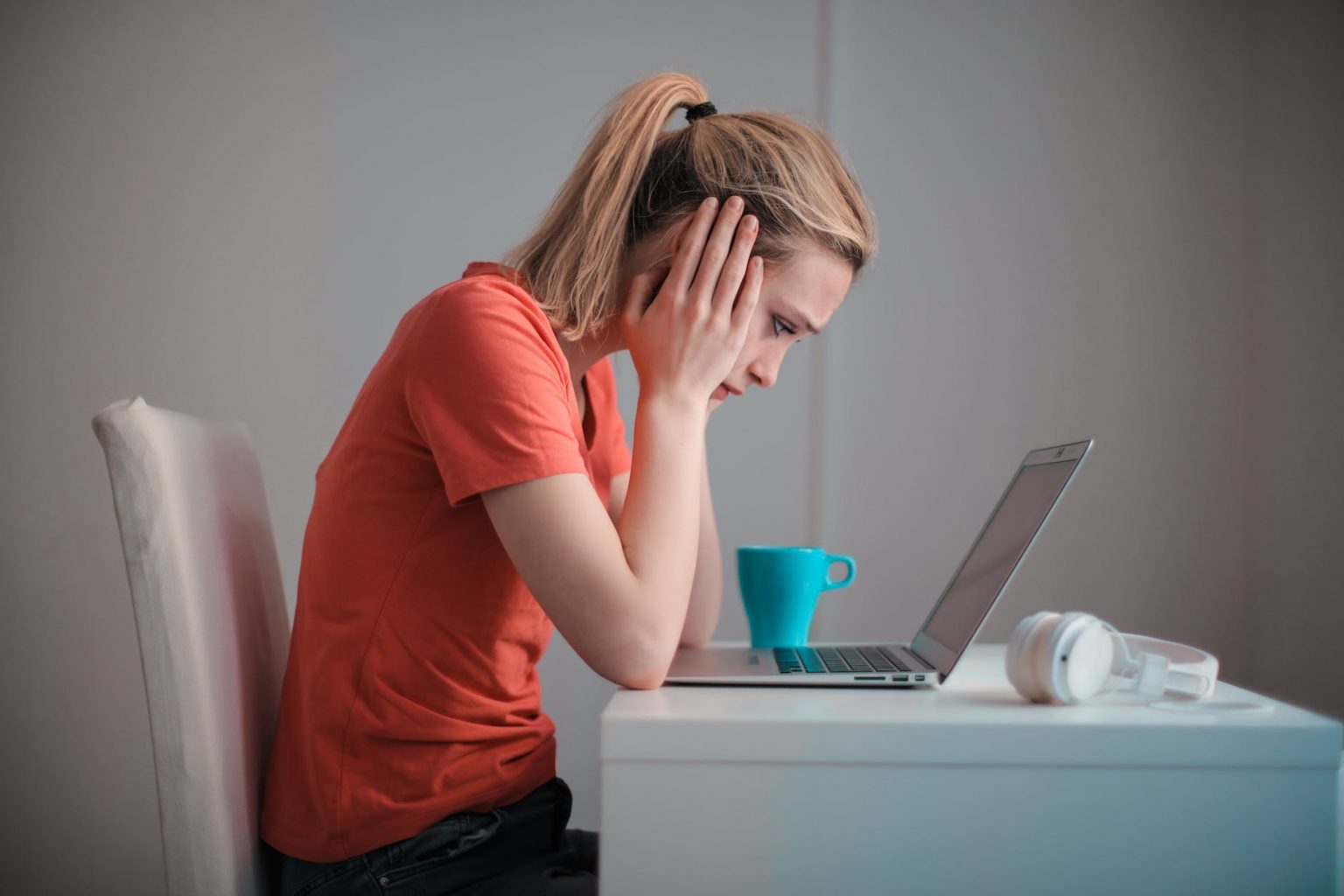 Frustrated woman working on laptop with hands on face.