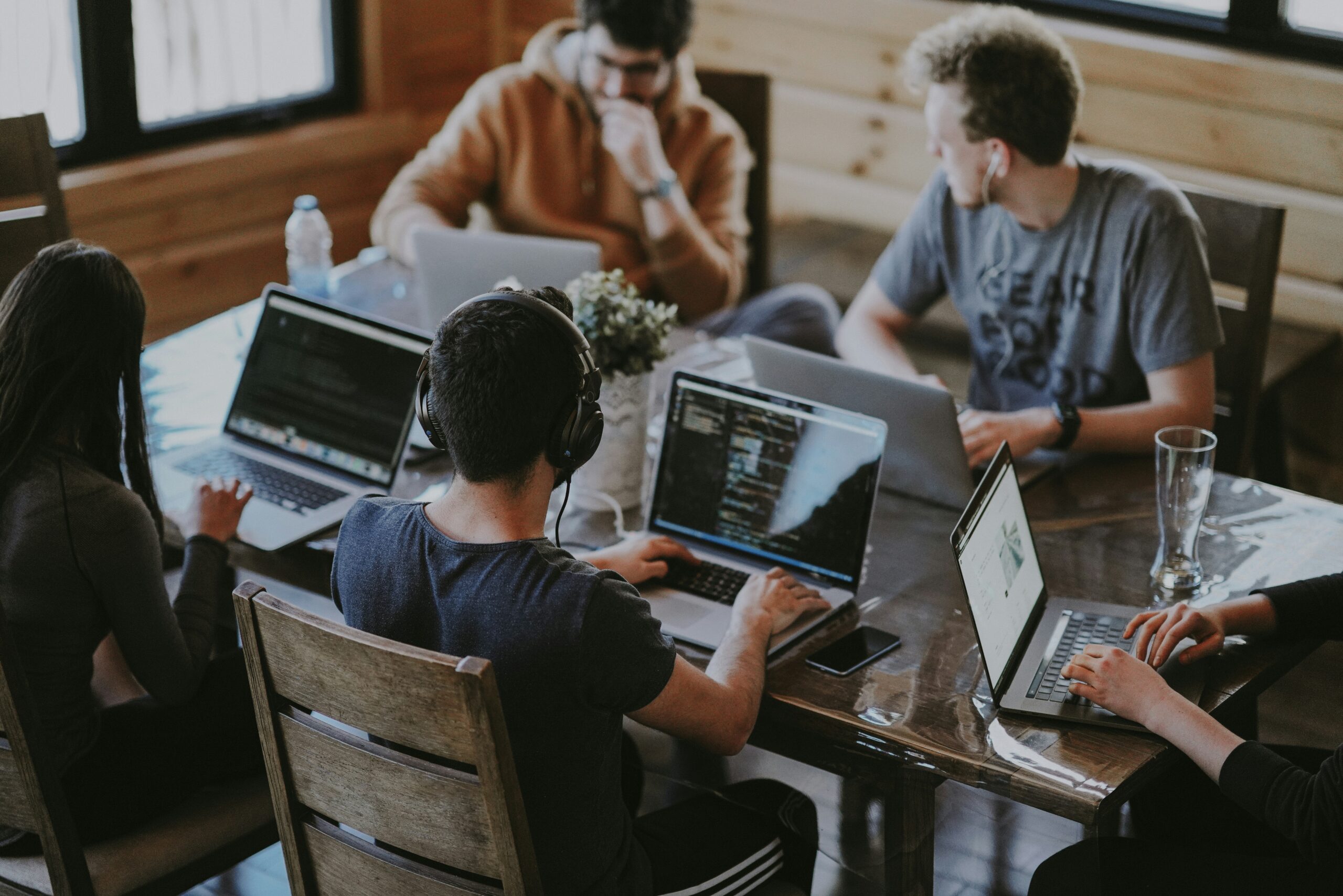 Group of young professionals collaborating on laptops in a casual workspace.