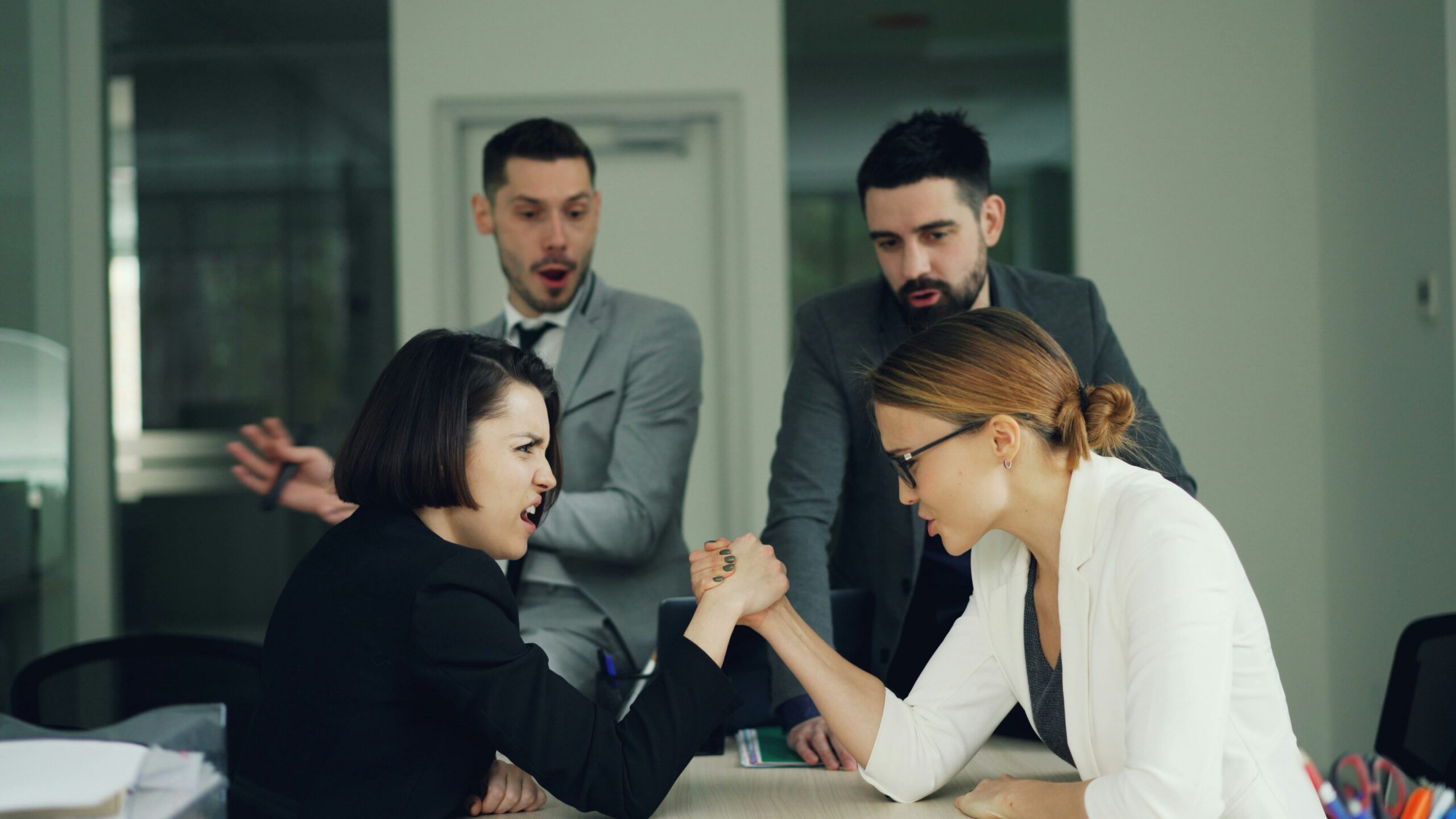 Two women arm wrestling while two men watch intently.
